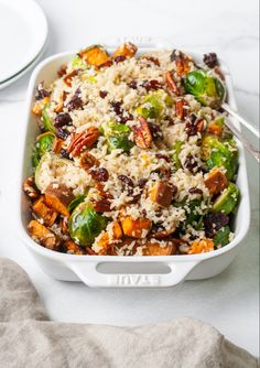 a white casserole dish filled with rice and vegetables