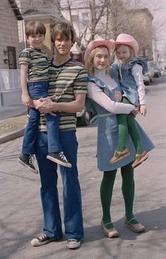 a man, woman and two children are standing on the street