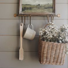 a painting hanging on the side of a wall next to a basket with flowers in it