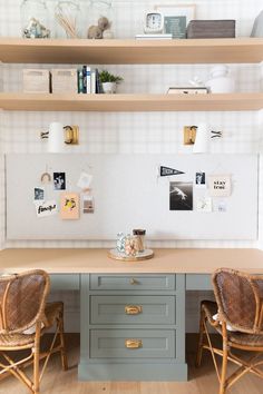 two chairs sitting at a desk in front of some shelves with pictures on the wall