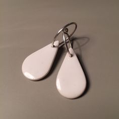 Simple, geometric earrings made of porcelain and white, glazing enamel. Drops measure approx. 2.5x1.5cm and sterling silver rings approx. 1.5cm. Boucles d'oreilles blanches, simples et originales en porcelaine émaillée. Les gouttes mesurent env. 2.5x1.5cm et sont montées sur des anneaux en argent véritable de 1.5cm de diamètre env. Modern Everyday Enamel Jewelry, Modern White Enamel Jewelry, Simple Nickel-free White Jewelry, Simple White Nickel-free Jewelry, Modern White Everyday Jewelry, White Enamel Minimalist Jewelry, White Modern Drop Earrings, Modern White Drop Earrings, Simple White Nickel-free Earrings