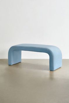 a blue bench sitting on top of a cement floor in front of a white wall