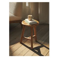 a small wooden table with a book and cup on it