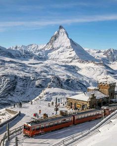 a train traveling down tracks next to a snow covered mountain range in the mountainside