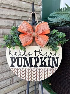 a wooden sign with an orange bow hanging from it's side next to a planter