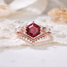 a close up of a ring with a red stone in the middle and diamonds around it