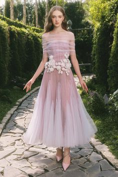 a woman in a pink dress standing on a stone path