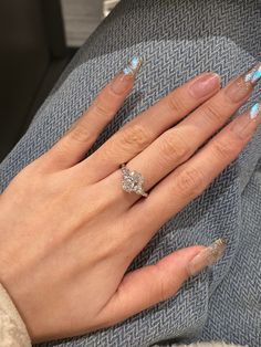 a woman's hand with blue and white nail polish holding a diamond engagement ring