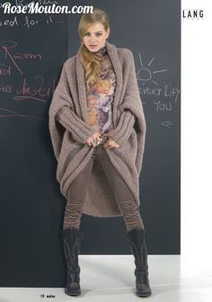 a woman standing in front of a blackboard wearing boots and a sweater with an animal print on it