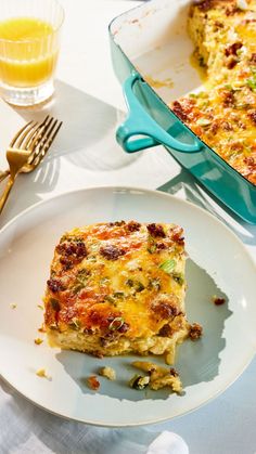 a white plate topped with a piece of quiche next to a glass of orange juice