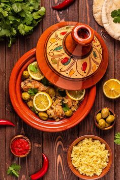 an orange plate with food on it next to some olives and lemons in small bowls