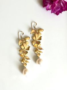 The listing is for one pair of dangle drop flower pearl earrings shaped like orchid earrings. The gold flower earrings use a beautiful freshwater pearl. Great for bridesmaids gifts of wedding jewelry. This listing is for the longer pair in the picture. I also sell a short dangle version. D E T A I L S - Gold plated brass floral orchid charm - 14k gold filled ear wire - Freshwater pearls wrapped with fine 14k gold fill wire - Light weight, comfortable to wear. ∙ EXTRA LOVE & ALOHA ∙ - Handcrafted Formal Dangle Flower Earrings With Pearl Drop, Delicate Dangle Flower Earrings For Bridesmaids, Formal Pearl Drop Dangle Flower Earrings, Formal Pearl Drop Flower Dangle Earrings, Elegant Flower Shaped Chandelier Earrings, Elegant Teardrop Earrings With Flower Charm, Rose Gold Flower Earrings With Pearl Drop, Delicate Gold Petal Flower Earrings, Elegant Pearl Drop Dangle Flower Earrings