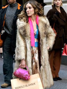 a woman in a fur coat carrying a pink handbag