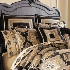 a bed with black and gold comforters on top of it's headboard