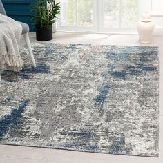 an area rug with blue and gray colors in a living room, next to a chair