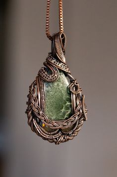 "Piece details: Handcrafted Copper Wire Wrapped Amulet featuring a high quality Seraphinite cabochon and 2 small green labradorite cabochons on a 45cm Copper Box chain. Chakras - All Chakras, especially the Heart  Zodiac - Sagittarius Planet- Earth Stone Details: Seraphinite is a variety of clinochlore, a mineral in the chlorite group that forms when lavas are altered by hydrothermal fluids. Most chlorite minerals form from altered minerals in basaltic type lavas that contain low silica and minerals such as pyroxenes and amphiboles or during low grade metamorphism Metaphysical Properties: Seraphinite is a stone of spiritual enlightenment.   Seraphinite is named after the biblical seraphs or seraphim angels. With some specimens the resemblance is quite strong, with shorter down-like feather Planet Wire Wrap, Handmade Green Spiritual Gemstones, Green Gemstone Jewelry With Labradorite, Green Labradorite Necklaces With Natural Stones, Handmade Green Labradorite Jewelry, Green Electroformed Bohemian Jewelry, Artisan Green Jewelry With Large Stone, Green Bohemian Electroformed Jewelry, Bohemian Green Electroformed Jewelry