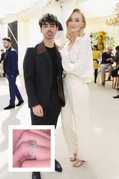 a man and woman standing next to each other in front of a white tent with people