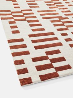 an orange and white area rug with squares on the top, in front of a white background