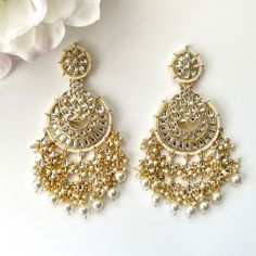 "Gorgeous intricately designed gold kundan statement earrings with beaded detailing and hanging cluster pearls. Length 4\" |  Width 1.7\" Items are carefully packed and ready for gifting. All pictures are taken in natural light please allow for slight variations in color due to camera settings. Jewelry Care ✨Protect your jewelry in a closed box or pouch   ✨Wear jewelry after you have applied lotion or perfume ✨Gently buff with a soft cotton cloth  Visit our website: www.desimoon.etsy.com Thank y Elegant Chandelier Earrings With Gota Work For Wedding, Festive Kundan Chandelier Earrings With Dangling Beads, Festive Temple Jewelry Chandelier Earrings With Dangling Beads, Gold Chandelier Earrings For Wedding And Festive Occasions, Gold Kundan Bridal Earrings For Reception, Kundan Dangle Chandbalis For Reception, Festive Gold Chandelier Earrings For Wedding, Elegant Chandbalis With Dangling Beads For Weddings, Gold Bridal Earrings For Reception And Festivals