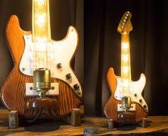 two electric guitars with lights on them are sitting on a table in front of a black curtain