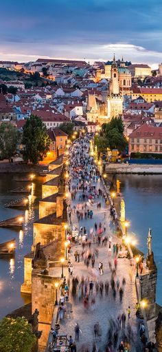 many people are walking on the bridge over the water at night in prague, czech