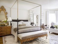 a bedroom with a canopy bed, white walls and rugs on the floor in front of it