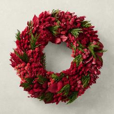 a christmas wreath with red flowers and greenery on the front, hanging on a wall