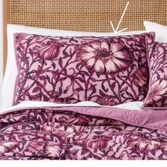 an image of a bed with purple and white flowers on the pillowcase, along with two pillows