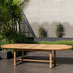 a wooden table sitting on top of a tiled floor next to potted planters