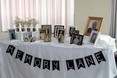 a table topped with pictures and framed photos next to a white table cloth that says memory lane