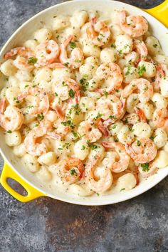 a yellow skillet filled with shrimp and macaroni on top of a table