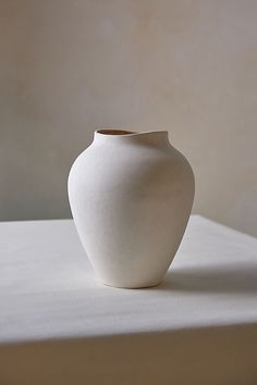 a white vase sitting on top of a table