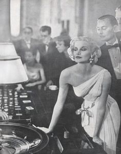 an old photo of a woman in front of a record player with other people behind her