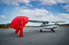 a woman in red is standing next to an airplane