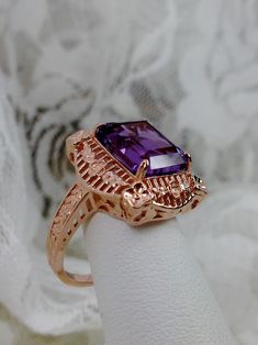 Natural Purple Amethyst Rose Gold plated Sterling Silver RingPicture Frame Design#D227 Inspired by Victorian era designs, this is a lovely reproduction ring. This lovely filigree handcrafted sterling silver ring is overlaid with rose gold plating. This flawless 5 carat Natural Purple Amethyst is 11mm x 9mm. The ring is 11/16" (17.5mm) North to South on the finger. The inside of the band is marked 925 for sterling silver. Notice the beautiful daisies on the outside of the setting and band. There Elegant Purple Amethyst Ring With Filigree, Elegant Purple Amethyst Filigree Ring, Wedding Jewelry With Filigree Amethyst, Elegant Gold Amethyst Ring With Intricate Design, Wedding Amethyst Filigree Jewelry, Elegant Amethyst Ring For Promise With Intricate Design, Elegant Amethyst Ring With Intricate Design For Anniversary, Elegant Amethyst Filigree Ring For Wedding, Elegant Filigree Amethyst Ring For Wedding