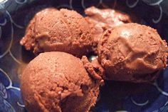 three scoops of chocolate ice cream in a blue bowl on top of a table