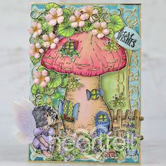 a card with an image of a mushroom house and fairy on the front, surrounded by flowers