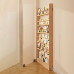 a bookshelf in the corner of a room with hard wood floors and white walls