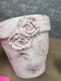 a hand holding a clay pot with flowers on it