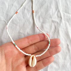 This is a white, teal, pink, orange, and gold beaded necklace! It is waterproof and tarnish free, and can be made with a silver or gold clasp! Handmade White Strand Beaded Necklaces, Handmade White Beaded Strand Necklace, White Necklace With Lobster Clasp For Festivals, White Festival Necklaces With Lobster Clasp, White Shell Necklace With Tiny Beads As A Gift, White Tiny Beaded Necklaces For The Beach, White Shell Necklace With Round Beads For The Beach, White Round Beads Shell Necklace For Beach, White Round Beads Beachy Jewelry