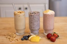 three smoothies are lined up on a table