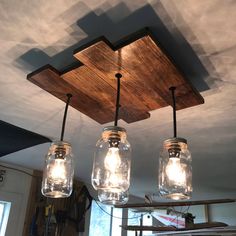 three mason jar lights hanging from the ceiling in a kitchen with wood planked ceilings