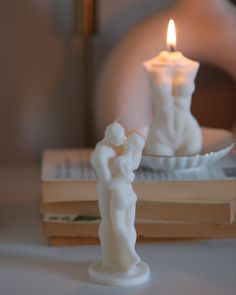 a candle that is on top of a book next to a plate with a figurine