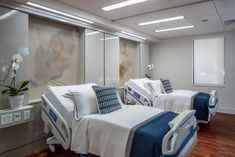 two beds in a hospital room with blue and white bedding