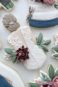 decorated cookies with flowers and laces on top of a white tablecloth covered in frosting