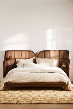 a large bed sitting on top of a wooden floor next to a white bedroom wall