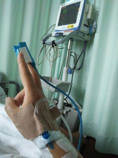 a person in a hospital bed with an iv and hand on the arm, next to a monitor