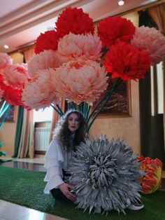 a woman sitting on the ground next to large flowers