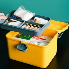 two yellow containers filled with medicine and other medical supplies on a black table next to a green wall