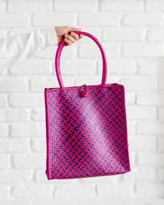 Fusia Pink Woven Bag With Handles, Straw Tote Bag, Shopping Tote BagOur totes are as functional as they are beautiful. Naturally dyed and lovingly handwoven, we know they will be a vibrant addition to your closet or as a gift. These totes are made by weavers in Chiangmai, Thailand where they use the Pandanus leaf as their material. 12"H x 11"W20"H x (with handle)The tote can hold up to 4lbs. Just enough to hold your MacBook.SOCIAL IMPACT | FAIR TRADE | HANDMADEYour purchase supports the basketry Purple Square Bags For Summer, Purple Square Bag For Summer, Pink Handheld Gift Bag, Summer Purple Square Bag, Pink Woven Pouch Bag, Pink Tote Shoulder Bag With Braided Handles, Pink Shoulder Bucket Bag With Braided Handles, Pink Square Crochet Bag For Beach, Pink Square Crochet Bag For The Beach